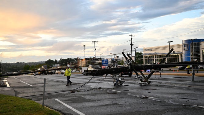 A utility worker stands near a downed utility pole in Westminster, Maryland, on Monday, August 7, 2023.