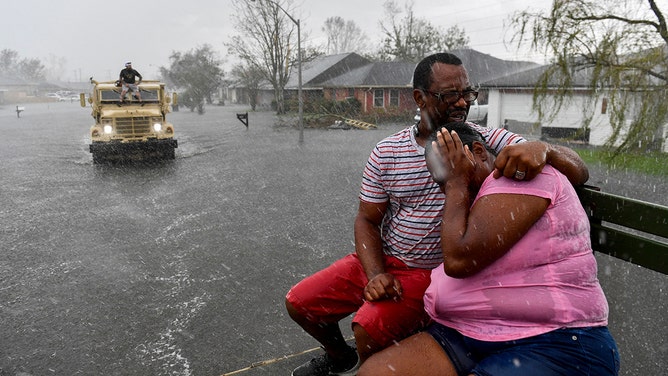 People react as a sudden rain shower soaks them with water while riding out of a flooded neighborhood in a volunteer high water truck assisting people evacuating from homes after neighborhoods flooded in LaPlace, Louisiana on August 30, 2021 in the aftermath of Hurricane Ida.