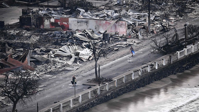 An aerial image taken on August 10, 2023 shows a person walking down Front Street past destroyed buildings burned to the ground in Lahaina in the aftermath of wildfires in western Maui, Hawaii.