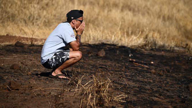 Maui resident John Rey Serrano reacts while looking from a road above Lahaina Town in the aftermath of a wildfire in Lahaina, western Maui, Hawaii on August 11, 2023. A wildfire that left Lahaina in charred ruins has killed at least 67 people, authorities said on August 11, making it one of the deadliest disasters in the US state's history. Brushfires on Maui, fueled by high winds from Hurricane Dora passing to the south of Hawaii, broke out August 8 and rapidly engulfed Lahaina. (Photo by Patrick T. Fallon / AFP) (Photo by PATRICK T. FALLON/AFP via Getty Images)