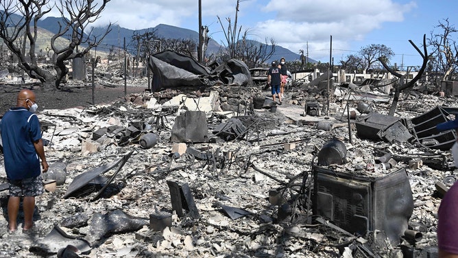 The Ganer family look through the ashes of their family's home on Malolo Place in the aftermath of a wildfire in Lahaina, western Maui, Hawaii on August 11, 2023.