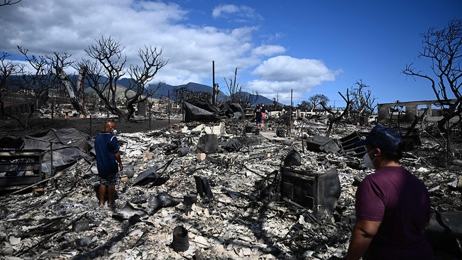 The Ganer family look through the ashes of their family's home on Malolo Place in the aftermath of a wildfire in Lahaina, western Maui, Hawaii on August 11, 2023.