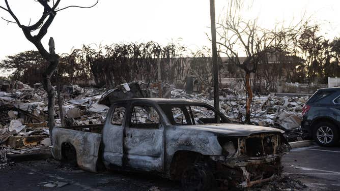 A burnt out car lies in the driveway of charred apartment complex in the aftermath of a wildfire in Lahaina, western Maui, Hawaii on August 12, 2023. Hawaii's Attorney General, Anne Lopez, said August 11, she was opening a probe into the handling of devastating wildfires that killed at least 80 people in the state this week, as criticism grows of the official response. The announcement and increased death toll came as residents of Lahaina were allowed back into the town for the first time.