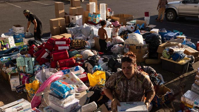 Volunteers sort out donations for those affected by a wildfire, at a parking lot in Lahaina, western Maui, Hawaii on August 12, 2023.