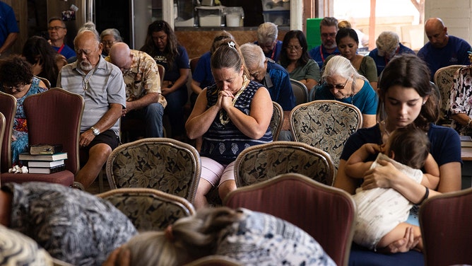 Survivors and churchgoers pray during a Sunday church service held by Pastor Brown of Lahaina's Grace Baptist Church, at Maui Coffee Attic in Wailuku, central Maui, Hawaii on August 13, 2023.