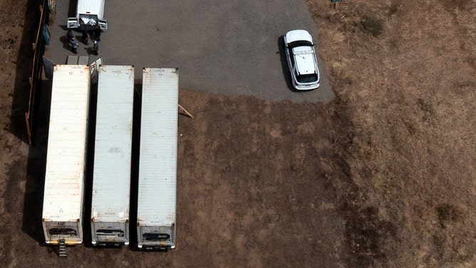 Workers move body bags into refrigerated storage containers adjacent to the Maui Police Forensic Facility where human remains are stored in the aftermath of the Maui wildfires in Wailuku, Hawaii on August 14, 2023.