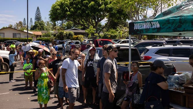 People wait in line to receive free meals at a distribution center for those affected by the Maui fires at Honokawai Beach Park in Napili-Honokowai, west of Maui, Hawaii, August 14, 2023.