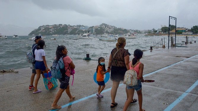 People walk along the coast in Acapulco, Guerrero State, Mexico, on August 16, 2023, following the passage of Tropical Storm Hilary.