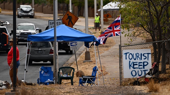 The Flag of Hawaii waves by a sign reading "Tourist Keep Out" in the aftermath of the Maui wildfires in Lahaina, Hawaii, on August 16, 2023.
