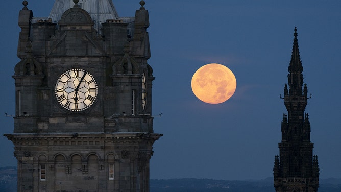 The super blue moon sets between the Balmoral Clock and the Scott Monument in Edinburgh on Thursday, August 31, 2023.