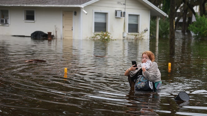 Makatla Ritchter wades through flood waters after having to evacuate her home when the flood waters from Hurricane Idalia inundated it on August 30, 2023 in Tarpon Springs, Florida. Hurricane Idalia is hitting the Big Bend area of Florida.