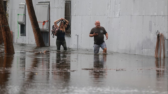 People wade through flood waters from Hurricane Idalia after it passed offshore on August 30, 2023 in Tarpon Springs, Florida. Hurricane Idalia is hitting the Big Bend area of Florida.
