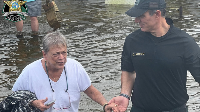 A woman is seen being helped through floodwaters in Pasco County, Florida.