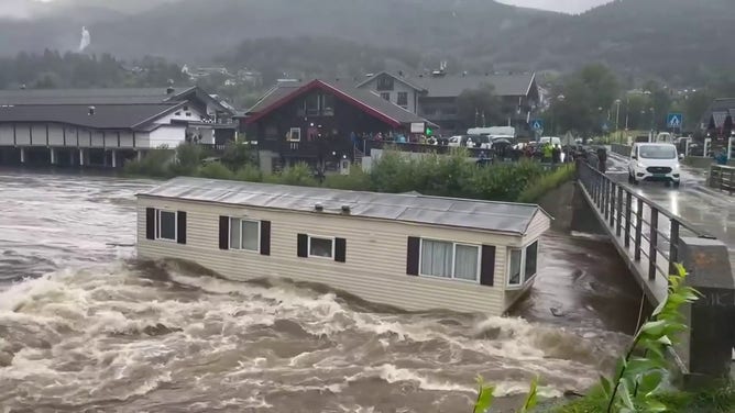 An image showing a home as it approached a bridge after being swept downstream by raging floodwaters during a powerful storm in Norway.