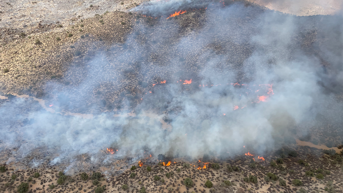 Smoke and flames rise above light vegetation on the York Fire, Mojave National Preserve.