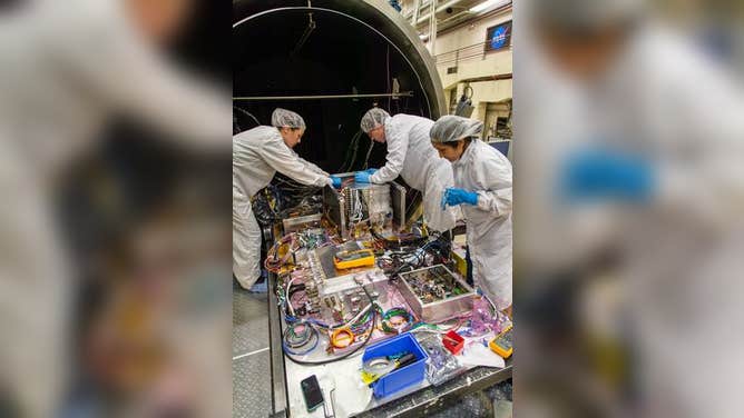 ComPair principal investigator Carolyn Kierans (NASA, left) and the University of Maryland Baltimore county’s Janeth Valverde Quispe (right) and Nicholas Cannady (back) work on ComPair ahead of thermal vacuum testing at NASA’s Goddard Space Flight Center in Greenbelt, Maryland, in this photograph.