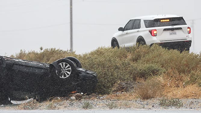 First responders keep watch near a vehicle that flipped over during rainfall from approaching Tropical Storm Hilary on August 20, 2023 near Palm Springs, California.