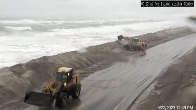 North Carolina DOT crews clearing sand and water from the roadway where they can.