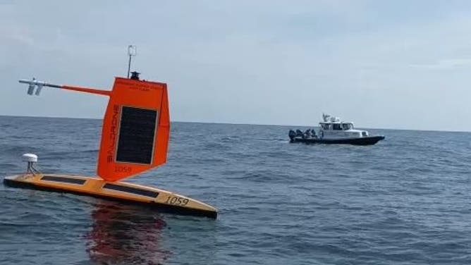 A Saildrone in the foreground, a ship in the background.