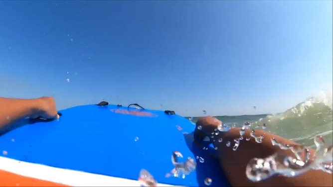 Houser swims through rough surf to reach the swimmer in trouble.