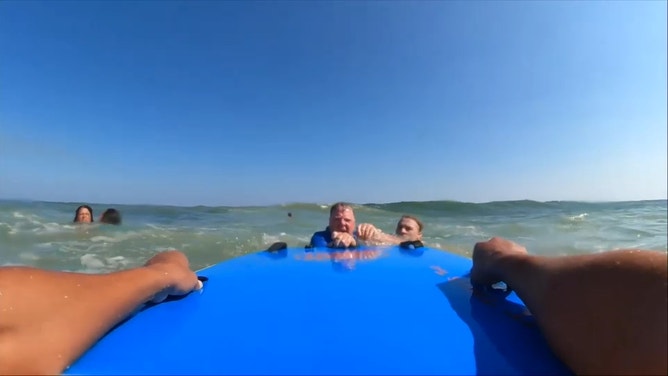 The swimmer, Gabriel, reaches for the tandem board.