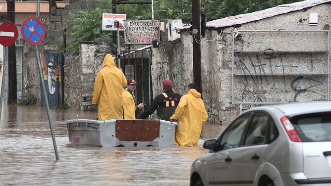 Firefighters and civilian security personnel stand in a flooded street in the city of Volos, central Greece, on September 6, 2023.