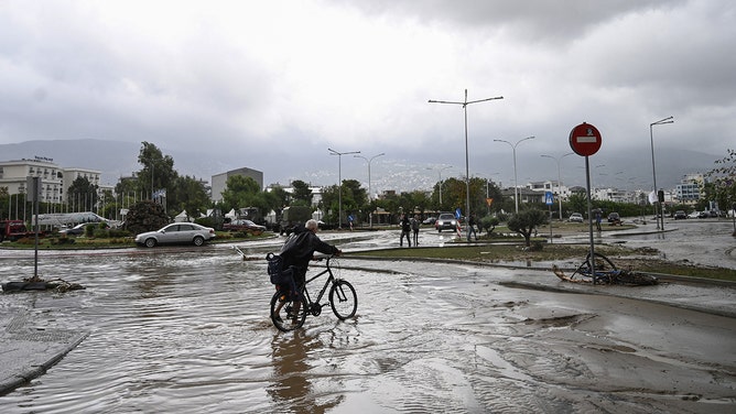 A man rides a bicycle in a flooded road in the city of Volos, central Greece, on September 6, 2023.