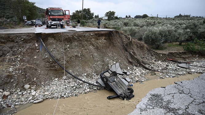 A picture taken on September 6, 2023 shows a car in the river bed after a road collapsed due to heavy floods in Kala Nera near the city of Volos, central Greece.
