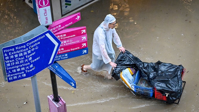 A man pushes a cart on a flooded road in Hong Kong on September 8, 2023.