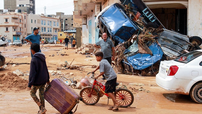 A boy pulls a suitcase past debris in a flash-flood damaged area in Derna, eastern Libya, on September 11, 2023. Flash floods in eastern Libya killed more than 2,300 people in the Mediterranean coastal city of Derna alone, the emergency services of the Tripoli-based government said on September 12.
