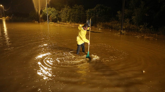 A man tries to open a blocked water drain in the middle of flooded road due to the Storm Daniel, which affected the city of Derna in Libya, in Deir Al Balah, Gaza on September 13, 2023.