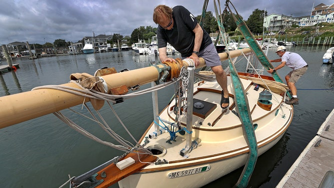 Mark Wiatrowski steps over his mast on board his boat "The Stray" that was in the process to be hauled out of the water in prep of an upcoming storm.