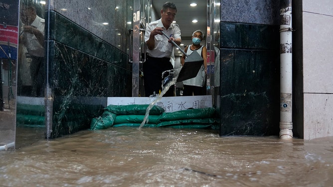 People sweep flood water from a house at Shau Kei Wan on September 8, 2023 in Hong Kong, China.