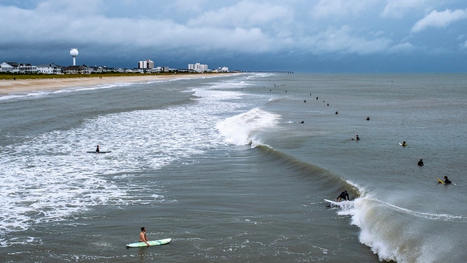 Surfers ride the waves as the ocean is whipped up by Tropical Storm Ophelia at Wrightsville Beach on September 23, 2023 in Wilmington, North Carolina.