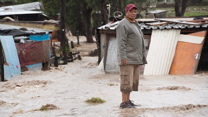 A man stands on mud brought there by a mudslide and heavy flooding as a result of a storm, close to his home, in Sir Lowry's Village, close to Somerset West on September 25, 2023.