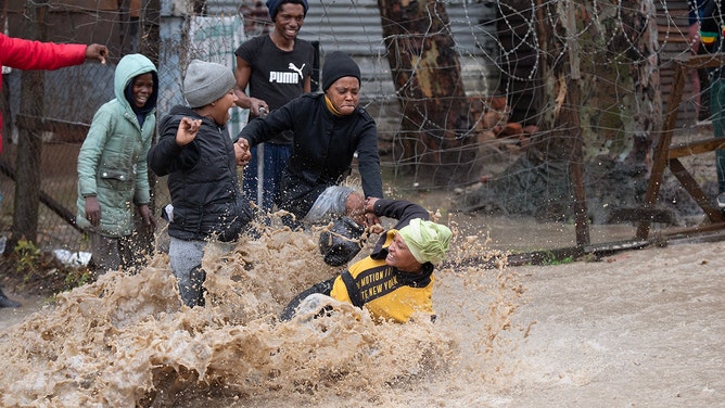 A woman falls in flooded street during heavy flooding as a result of a storm in Sir LowryÕs Village, close Somerset West on September 25, 2023.