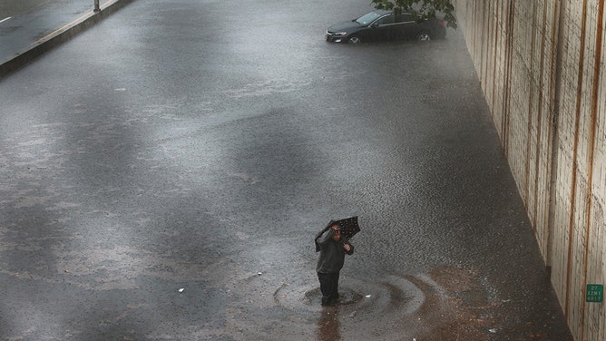 A person walks away from his vehicle after it got stuck in high water on the Prospect Expressway during heavy rain and flooding on September 29, 2023 in New York City.