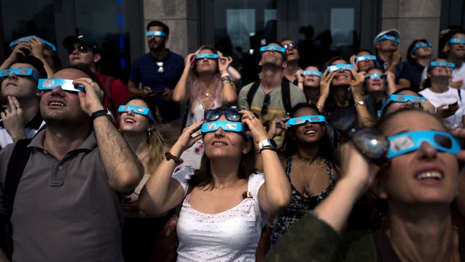File photo: People view the solar eclipse at 'Top of the Rock' observatory at Rockefeller Center, August 21, 2017 in New York City. While New York City is not in the path of totality for the solar eclipse, around 72 percent of the sun will be covered by the moon during the peak time of the partial eclipse.