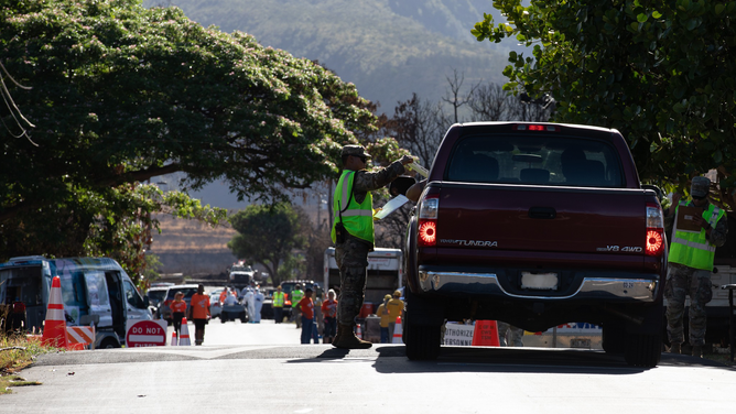 A driver is seen receiving information about the return to property devastated by deadly wildfires in Lahaina, Hawaii.