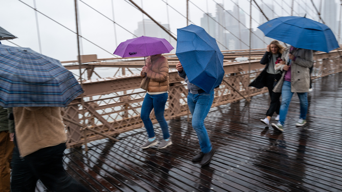 People walk over the Brooklyn Bridge during heavy rain and high winds as the remnants of Tropical Storm Ophelia continue to move through the area on September 25, 2023 in New York City. Much of the northeast U.S. saw a weekend of heavy rain and wind as the slow moving storm lingered from the Carolinas to New York City.