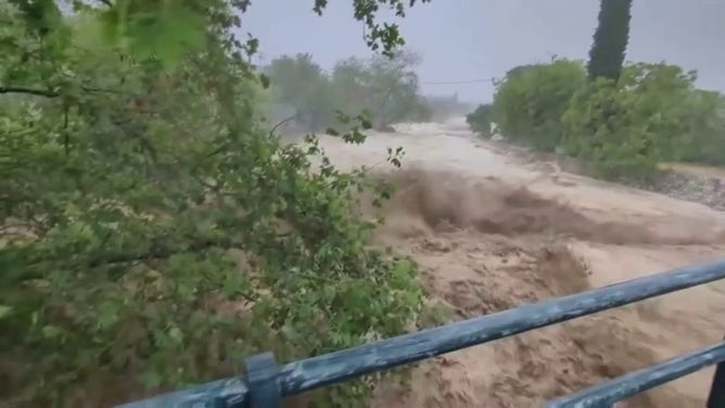 A river rages in Greece after torrential rain led to flooding.