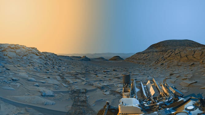 NASA’s Curiosity Mars rover used its black-and-white navigation cameras to capture panoramas at two times of day on April 8, 2023. The panoramas were captured at 9:20 a.m. and 3:40 p.m. local Mars time, then merged together. Color was added for an artistic interpretation of the scene, with blue representing the morning panorama and yellow representing the afternoon one. The resulting 