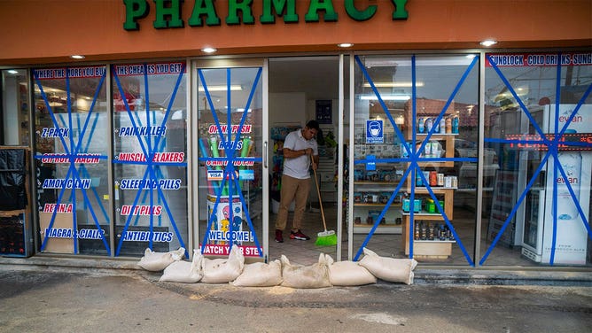 A pharmacy worker protects the shop from the arrival of Hurricane Norma at Los Cabos in Baja California State, Mexico, on October 20, 2023. Hurricane Norma on Friday once again strengthened to a Category 3 storm as it approaches a tourist hotspot on Mexico's Pacific coast. The hurricane -- which at one point was a Category 4 out of five on the Saffir-Simpson scale -- is now packing maximum sustained winds of 195 kilometers per hour (120 miles per hour), the US National Hurricane Center said in its latest update. It had been a Category 2 storm earlier in the day.