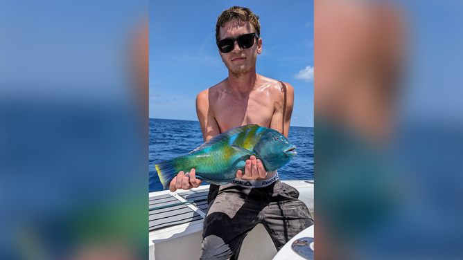 Connor Stone, 30, holding a colorful puddingwife fish.