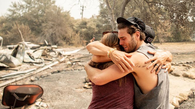 TOPSHOT - Resident Austin Giannuzzi cries while embracing family members at the burned remains of their home during the LNU Lightning Complex fire in Vacaville, California on August 23, 2020. - Firefighters battled some of California's largest-ever fires that have forced tens of thousands from their homes and burned one million acres, with further lightning strikes and gusty winds forecast in the days ahead. (Photo by JOSH EDELSON / AFP) (Photo by JOSH EDELSON/AFP via Getty Images)