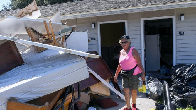 KISSIMMEE, FLORIDA, UNITED STATES - 2022/10/07: Mirta Marangi stands in front of a pile of her furniture which was ruined when several feet of water from Hurricane Ian flooded her apartment at the Kissimmee Homes Apartments in Kissimmee, Florida. Most of the apartments suffered substantial flood damage and residents were ordered to evacuate their homes by today so that work crews can begin the clean up and repair process. (Photo by Paul Hennessy/SOPA Images/LightRocket via Getty Images)