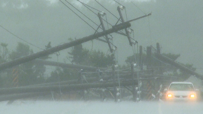 A car passes by power lines downed by the high winds from Typhoon Koinu in Taiwan's southern Pingtung County on October 5, 2023.