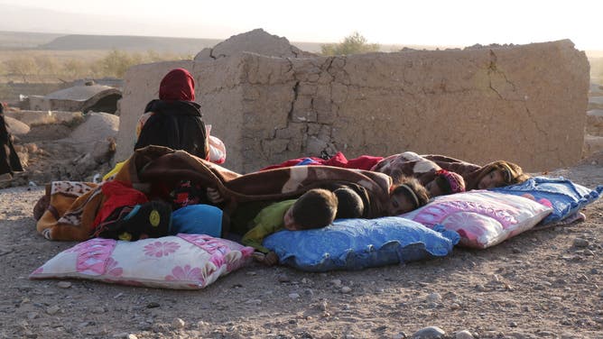 Afghan children rest under a blanket beside damaged houses after earthquake in Sarbuland village of Zendeh Jan district of Herat province on October 7,2023.