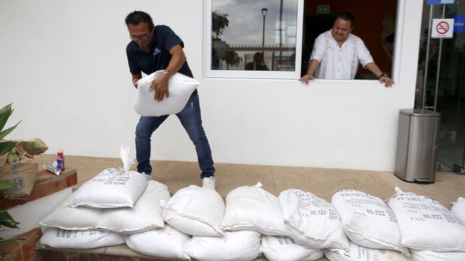 A man places sandbags next to a structure.