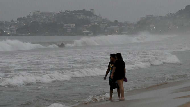People stand on the beach after Hurricane Otis' arrival alert in Acapulco, Guerrero state, Mexico on October 24, 2023.